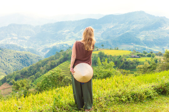 A woman admires the breathtaking scenery of rice terraces. Mu Cang Chai rice terraces on the mountain slopes.