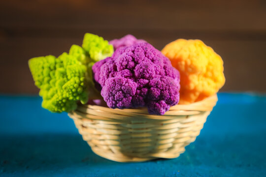 Multicolored cauliflower in a wicker bowl. Purple, yellow, and green florets.