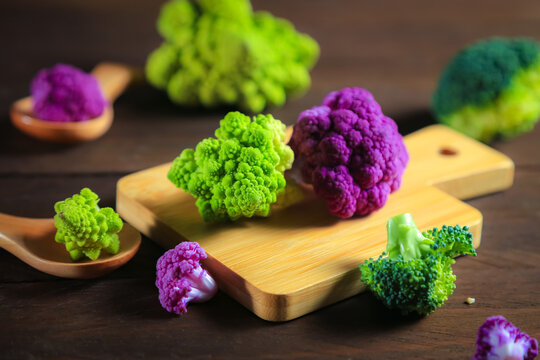 Multicolored cauliflower on a wooden table. Purple and green florets.