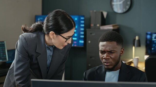 Caucasian young adult woman and African American young adult man analyzing data on computer in cybersecurity office. Footage suitable for computer security promos and corporate technology advertising