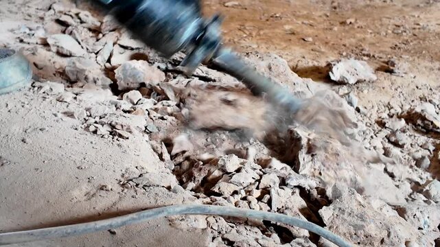 Close-up of demolition hammer chisel breaking concrete into rubble