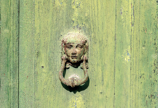 antique metal door knocker, green background