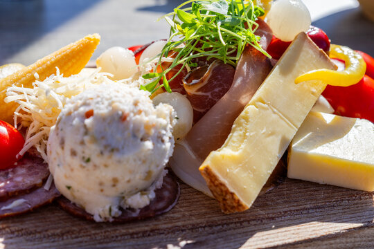 Close view of a traditional Austrian Brettjause in Tyrol served on a rustic oval wooden platter over a sunlit wooden table.