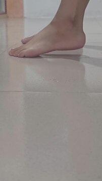 a bare foot lightly tapping a clean tiled floor, showing the natural position and texture of the toes and foot. Suitable for commercial concepts related to foot movement, tapping, rhythm, balance