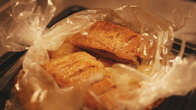 Close-up of juicy roasted duck breast fillets inside an open baking bag on an oven tray. Hot cooked poultry ready for dinner in a home kitchen. Homemade meat dish cooked in an oven.