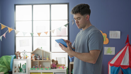 Man tapping tablet screen with finger while holding device in a toy filled room in building  quiet concentration. © Krakenimages.com