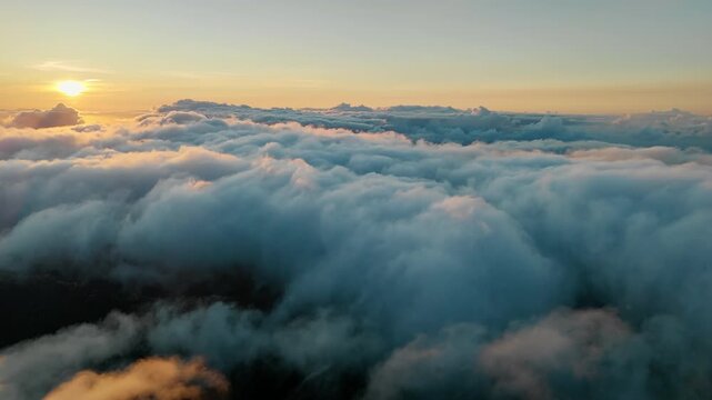Golden sunrise above billowing clouds beneath clear upper sky. Early daylight at beginning of new day