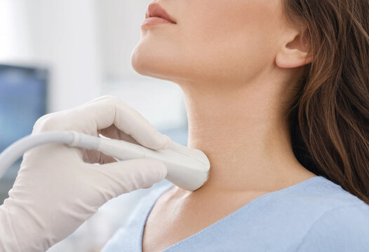 Adult woman receives a neck ultrasound examination from a medical professional in a clinical setting. Healthcare diagnostic procedure and patient care concept.