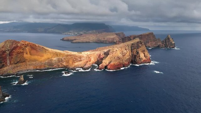 Long volcanic headland of Ponta de Sao Lourenco with steep cliffs in Atlantic Ocean, Madeira, Portugal. Aerial coastal footage
