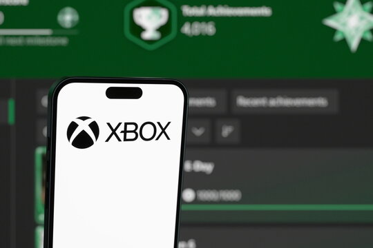 Low-angle view: the Xbox logo displayed on a smartphone screen. Xbox Launches Mythic Achievements, Its Answer to PlayStation Platinum Trophies. September 30, 2026, Lisbon, Portugal.