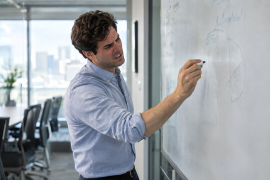 Businessman frustrated by empty whiteboard marker in meeting room