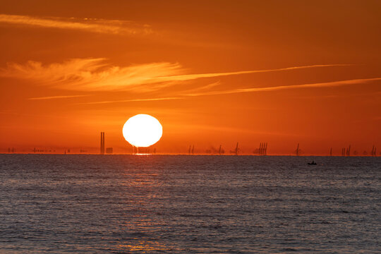 Luc-Sur-Mer, France - 08 08 2022:  Colorful sunrise over the sea and port of Le Havre far away