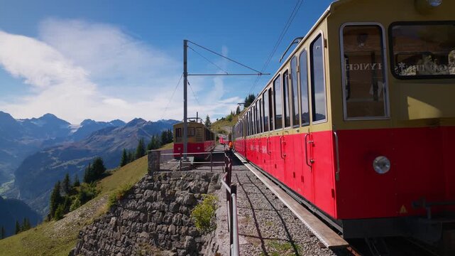 Vintage Schynige Platte cogwheel train in the Bernese Oberland, Switzerland, showing traditional red and cream railway carriages against a Alpine mountain backdrop, close-up view