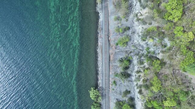 Split frame of train tracks including lake and shoreline.
