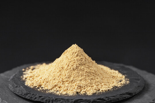 legume plant fenugreek powder on a black slate stone tray