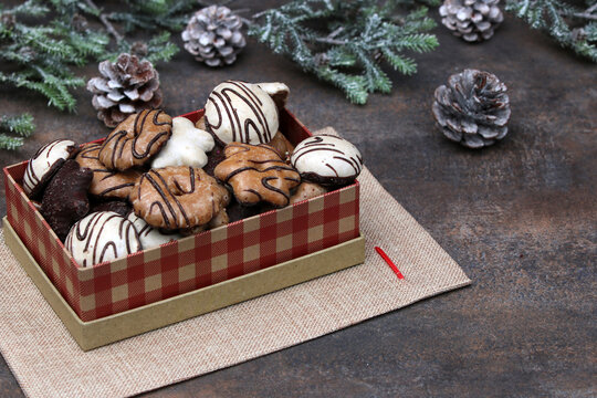 Verschiedene Lebkuchen mit Schokoladenglasur in einer rot-karierten Geschenkbox.