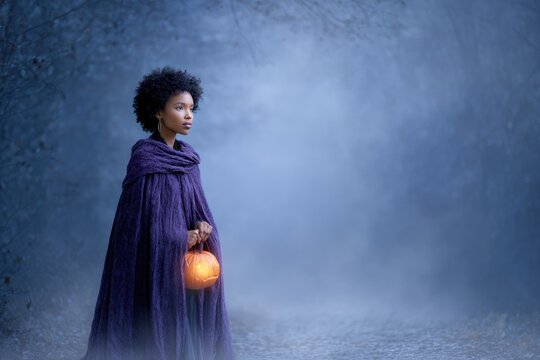 Mysterious young woman in purple cloak holding lantern in enchanted forest