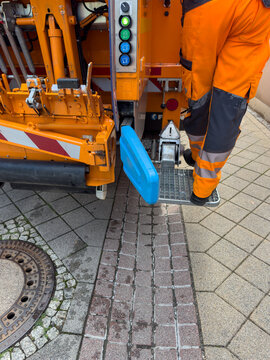 Orange garbage truck collecting waste in Germany