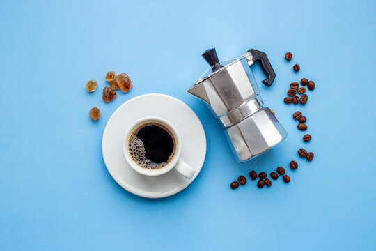 Fresh black coffee brewed in moka pot with coffee leaves - natural coffee experience and morning ritual, top view