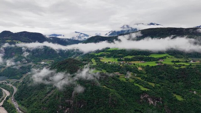 Broad mountain valley with forested slopes and low clouds in Dolomites, South Tyrol, Italy. Aerial landscape