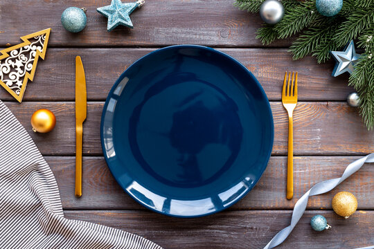 Empty plate with fir tree branch and blue colored decoration. Table setting top view