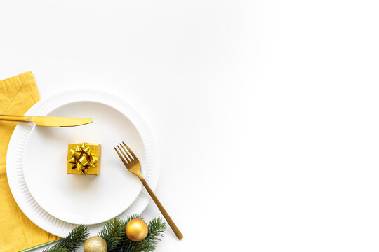 Empty plate with fir tree branch and yellow and gold colored decoration. Table setting top view