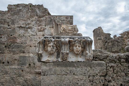 Side Ancient City. This photograph shows Medusa or theater mask reliefs displayed among ancient stone ruins.