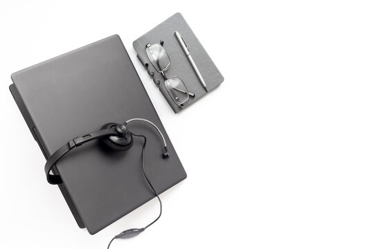 Remote customer support workspace - laptop, headset, notebook and glasses in soft natural light, top view