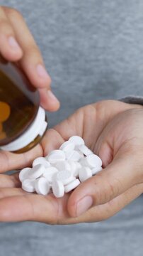 close up woman hand holding a medicine, with pours the pills out of medicine bottle. Stop drug use Taking Medication Caring for the health care medical concept.