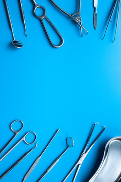 Pattern flat lay of stainless surgical instruments and tools on blue table, top view. Medical background
