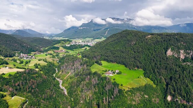 Alpine villages and green meadows in South Tyrol, Italy. Aerial footage of rural mountain landscape with scattered farmhouses