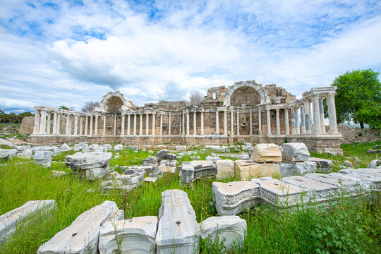 The Ancient City of Side. This photograph shows the remains of an ancient Nymphaeum (monumental fountain). In the background, there are columns, arches, and the tall, majestic stone fa&ccedil;ade of the anci