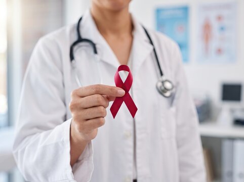 Doctor holding red awareness ribbon for HIV, aids, and world health campaign in medical clinic
