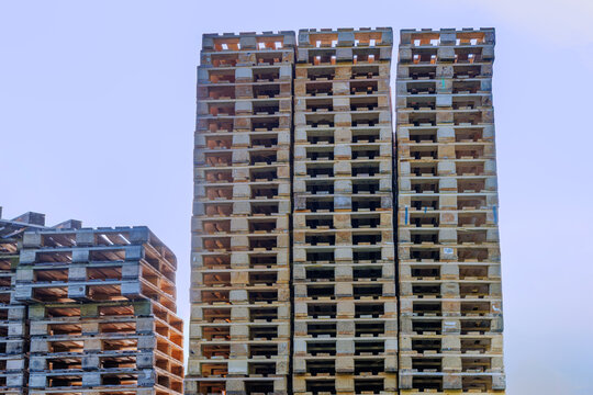 Tall stacks of wooden euro pallets against a clear sky, logistics, warehouse storage, freight transport and recycling concept
