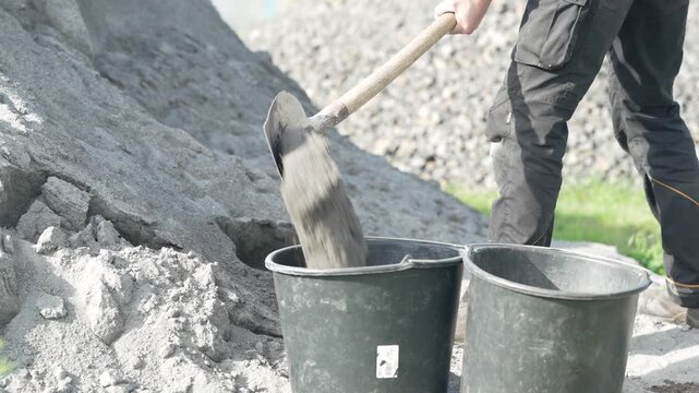 Worker loads gravel into buckets near a pile