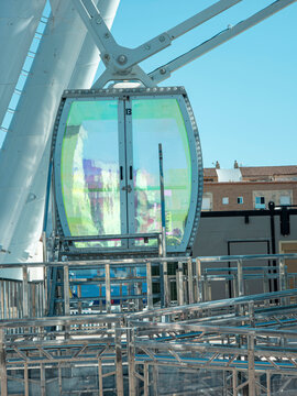 Glass Ferris wheel cabin number at the boarding platform on a sunny day