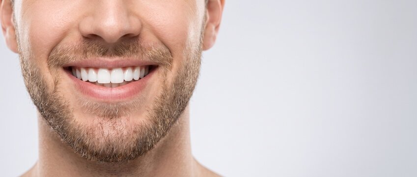 Perfect white male smile close-up. Handsome man with healthy teeth and beard. Dental care, whitening and stomatology concept. Long horizontal website header banner with copy space