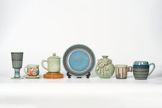 Collection of traditional Thai celadon ceramic dishware and pottery on white background.