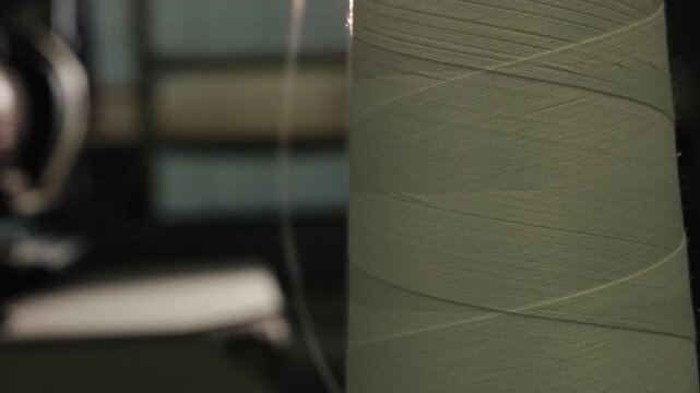 Industrial setting, thread manufacturing, illuminated fabric. Flare light casts glow on white thread spool factory.