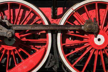 Wheels of an old steam locomotive. Vintage red-and-white locomotive wheels and the rod driving the wheel. © VLAD ANTONOV