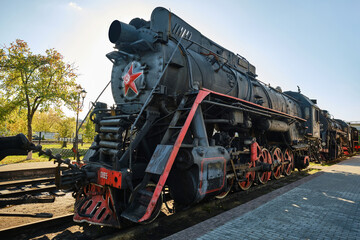 Moscow, Russia - September 30, 2026: Steam locomotives with red star stands on the railroad tracks in the museum exposition. Retro steam train. Locomotive depot, railway in the city. © VLAD ANTONOV