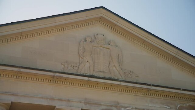 Close-up of the ornate pediment atop the Hall of Springs in Saratoga Springs, New York, featuring classical sculpted figures and detailed architectural moldings.