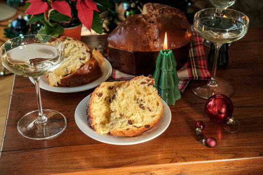 Festive Christmas Table With Sliced Panettone, Candle, Wine Glasses and Decorated Tree