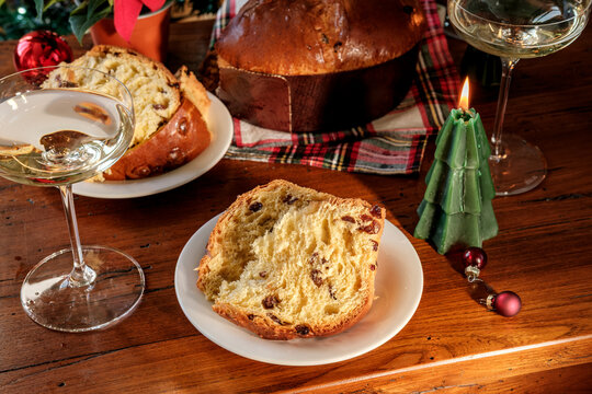 Festive Christmas Table With Sliced Panettone, Candle, Wine Glasses and Decorated Tree