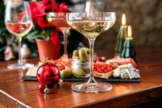 Festive Holiday Table With White Wine Glasses, Cheese Board, Olives and Christmas Tree Decorations