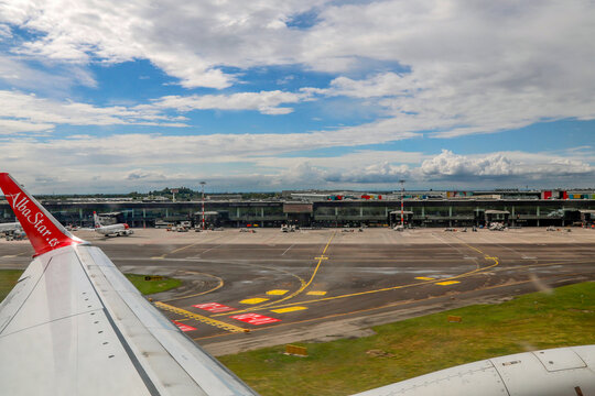 View of Milan Bergamo Airport tarmac and terminal buildings from the wing of an AlbaStar airplane prior to takeoff.