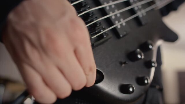 Caucasian teenager musician plugging audio jack cable into electric bass guitar socket. Footage fits music education campaigns, rock band rehearsal scenes and audio equipment commercials