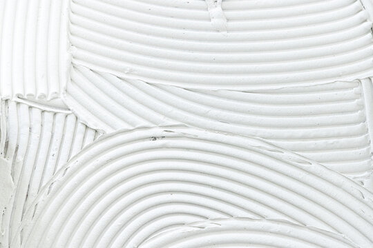 White tile adhesive spread with notched trowel. Prepared floor or wall for ceramic tiles installation