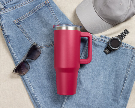 Blank dark red 40oz tumbler mockup, travel thermos on denim near mens accessories, copy space