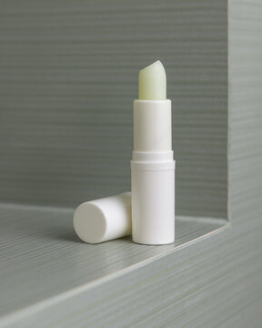 Open lip balm stick mockup with a lid in light green bathroom. Herbal cosmetic product for daily use